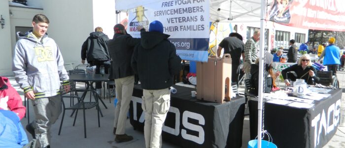 Not Forgotten Outreach tent at Taos Ski Valley. Banner: "Free yoga for servicemembers, veterans, & their families."